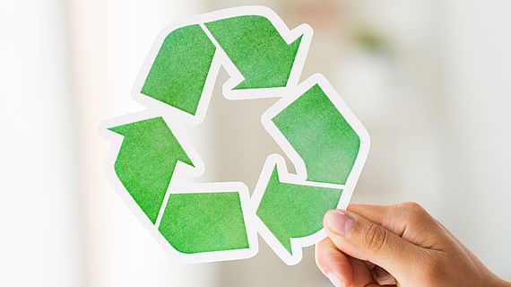 close up of hand holding green recycle symbol
