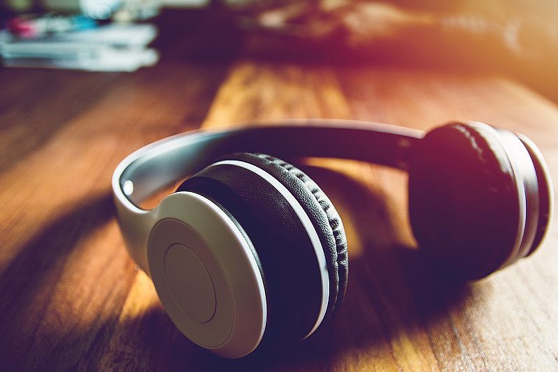 White Headset on wooden table with sunset and instagram style filter photo vintage tone