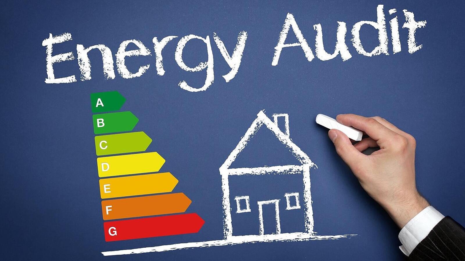Eine Hand hält ein Stück weiße Kreide. Daneben steht in Kreideschrift: 'Energy Audit' mit einem Haus, aus dessen Schornstein Euro-Zeichen kommen. Daneben eine Skala der Energieeffizienzklassen A++ bis G.
