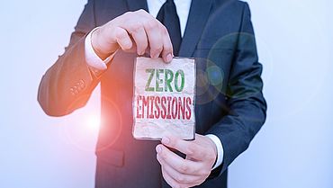 Handwriting text Zero Emissions. Concept meaning emits no waste products that pollute the environment Male human wear formal work suit office look hold notepaper sheet use hand.