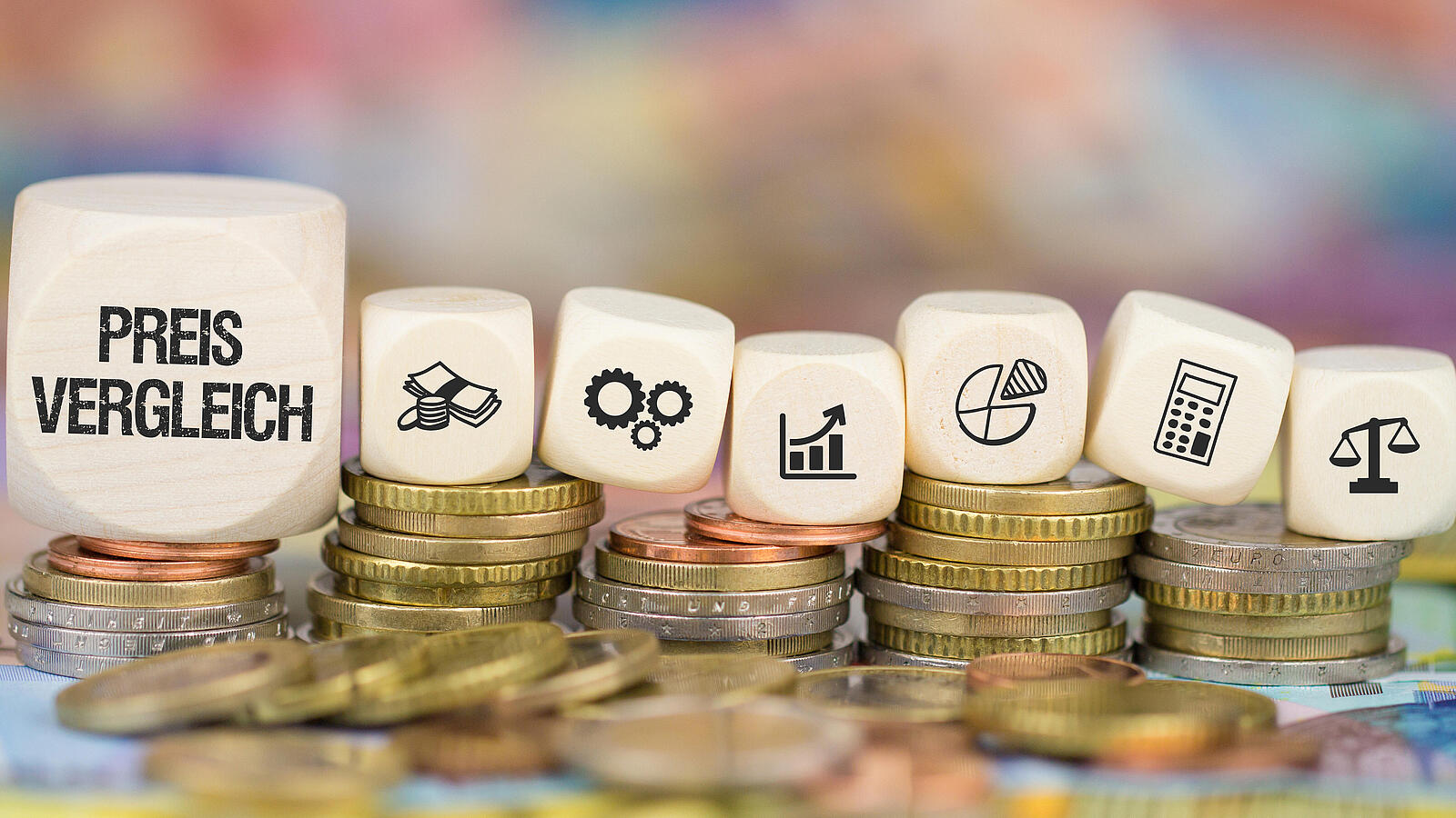Holzwürfel mit Symbolen für Geld, Diagramme und Waage liegen auf gestapelten Münzen, größter Würfel zeigt Preisvergleich.