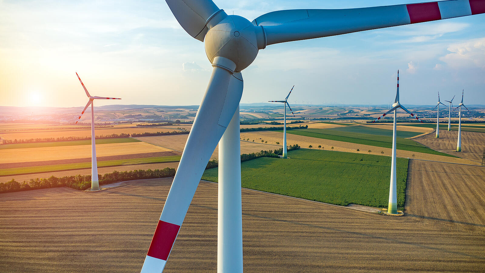 Windräder auf Acker und Feldern bei Sonnenuntergang