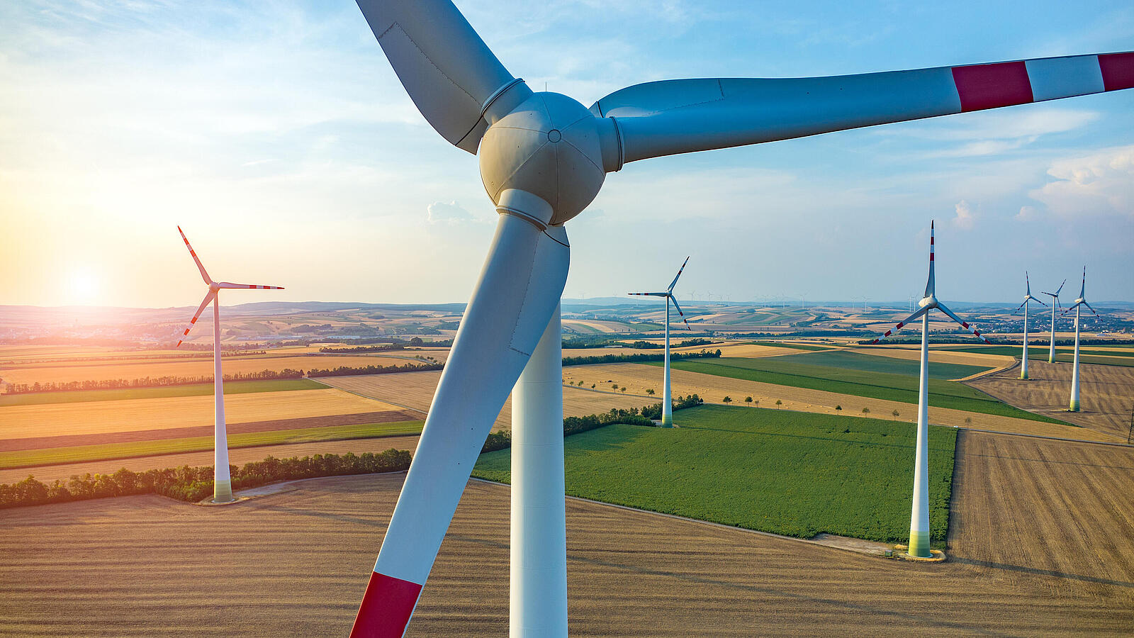 Windräder auf Acker und Feldern bei Sonnenuntergang