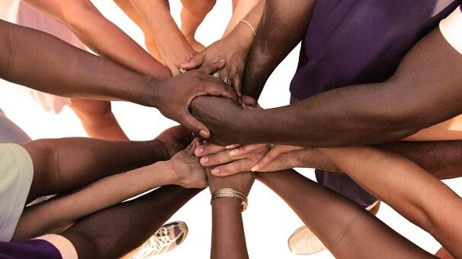 Mehrere Menschen legen ihre Hände übereinander als Zeichen von Gemeinschaft