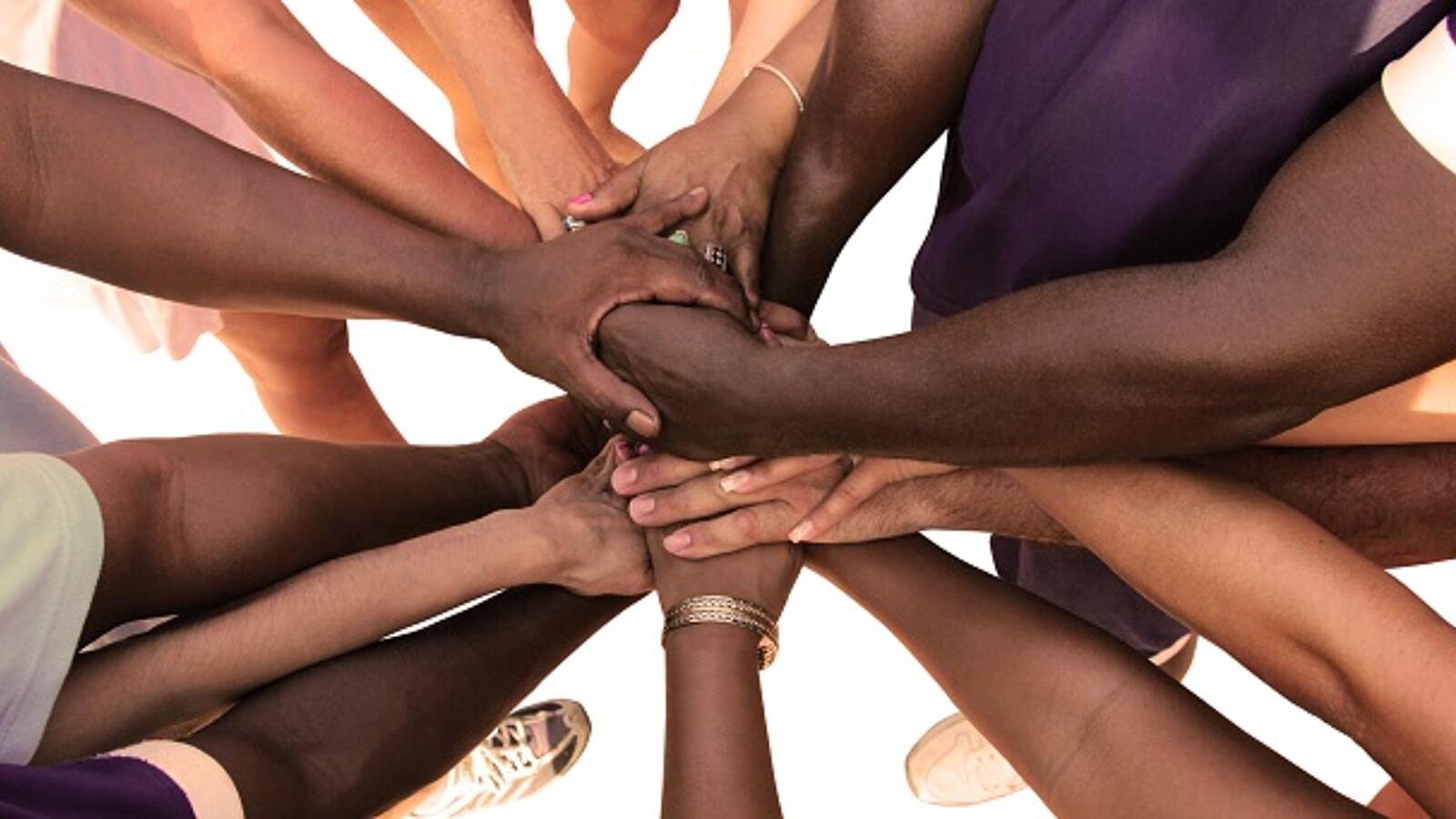 Mehrere Menschen legen ihre Hände übereinander als Zeichen von Gemeinschaft