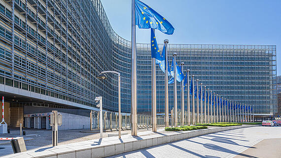 Das Berlaymont-Gebäude in Brüssel mit Europa-Fahnen im Vordergrund. 