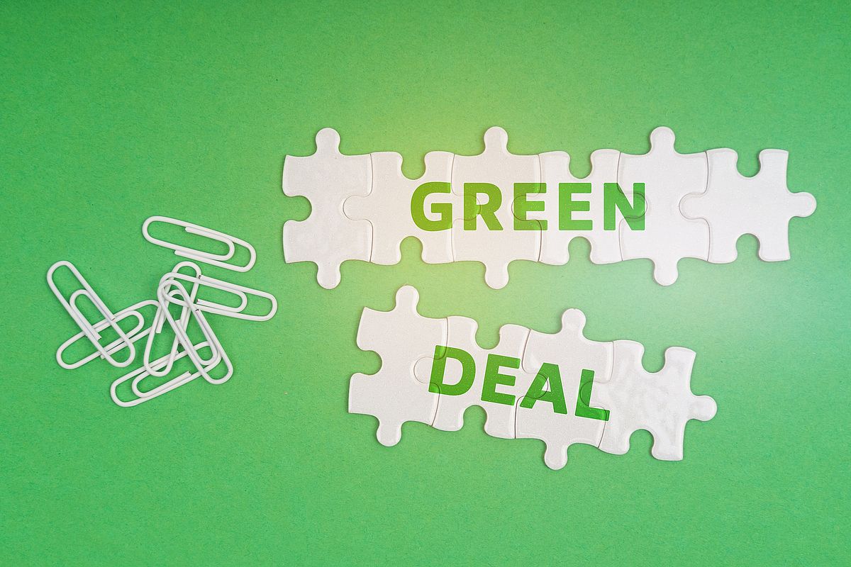 On a green background, paper clips and white puzzles with the inscription - Green Deal