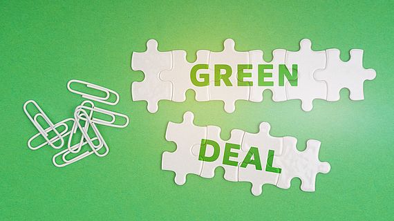 On a green background, paper clips and white puzzles with the inscription - Green Deal On a green background, paper clips and white puzzles with the inscription - Green Deal