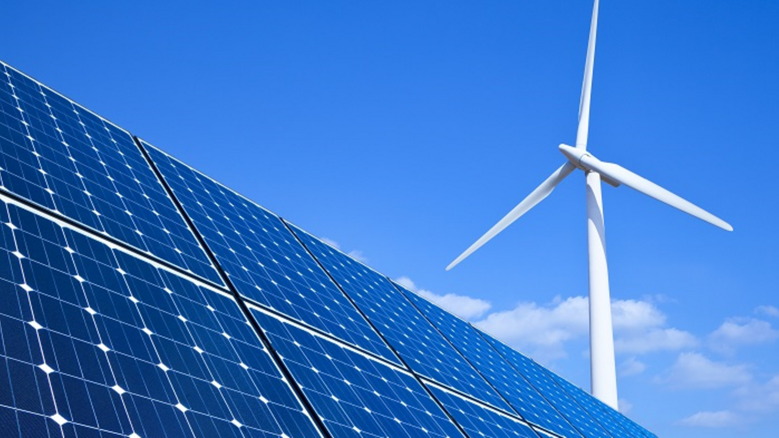 Froschperspektive auf ein Solarpanel mit einem Windrad im Hintergrund