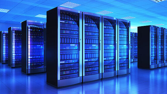 Ein Serverraum mit mehreren großen Server-Racks, die in bläulichem Licht beleuchtet sind. Der Boden ist glänzend und reflektiert das Licht, während die Deckenbeleuchtung gleichmäßig verteilt ist. Die Racks sind voll mit verschiedenen Speichergeräten.
