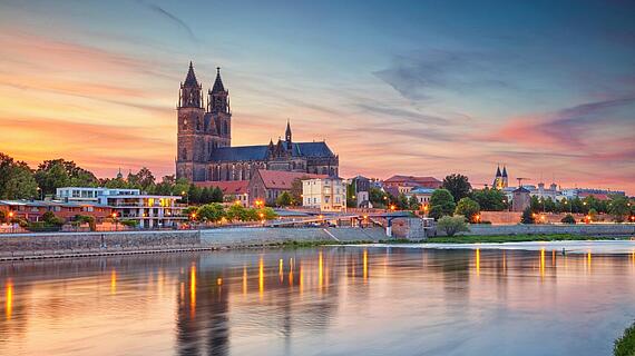 Der Dom von Magdeburg im Hintergrund, die Elbe im Vordergrund bei Sonnenuntergang.